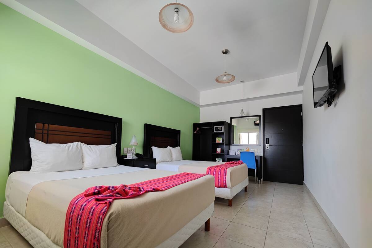 A hotel room with two beds, a desk, a chair, a TV, and a wardrobe.