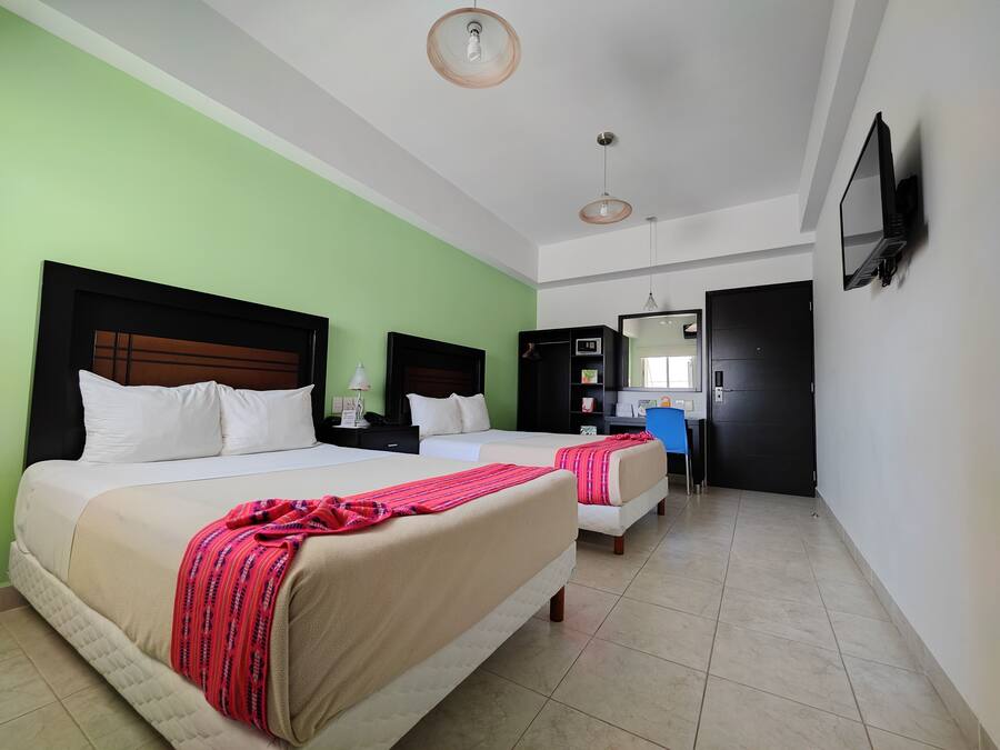 A hotel room with two beds, a desk, a chair, a TV, and a wardrobe.