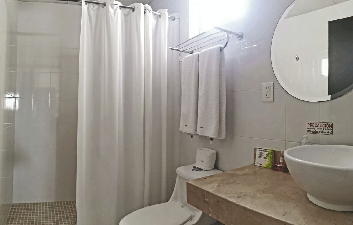 A bathroom with a shower, toilet, sink, and towel rack.