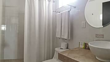 Un baño con ducha, inodoro, lavamanos y toallero.