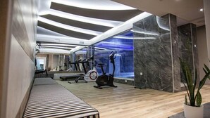 A modern gym with exercise equipment, a bench, and a large mirror. - Bella Mare (Rethymno)