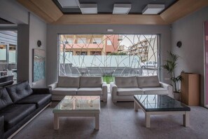 A modern living room with two sofas, a glass coffee table, and a large window with a view of buildings.
