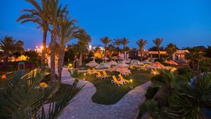Un resort con piscina, palmeras y tumbonas.