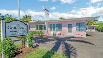 The Gondolier Inn in Naples, Florida, featuring a pink building with a classic design, a signboard, and a parking area.