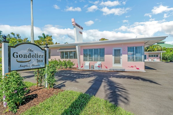 The Gondolier Inn in Naples, Florida, featuring a pink building with a classic design, a signboard, and a parking area. - The Gondolier Inn (Naples)