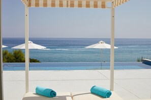 A poolside area with a view of the sea, two white umbrellas, and two blue towels on lounge chairs. - Sentido Louis Plagos Beach (Zakynthos)