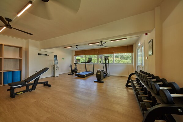 A gym with exercise equipment, a water dispenser, and a bench.
