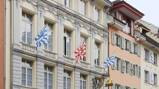 Ein mehrstöckiges Hotel mit einer klassischen Fassade, mit einem zentralen Eingang und einem Schild mit der Aufschrift 'HOTEL'.