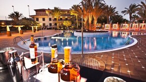 A poolside area with lounge chairs and a bar area with bottles and glasses. - Elba Palace Golf Boutique Hotel (Antigua)