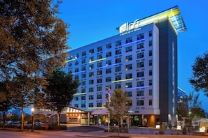 A multi-story hotel with a modern facade, illuminated signage, and a well-lit entrance area.