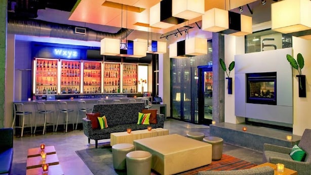 A modern bar area with a neon sign, seating arrangements, and a fireplace. - Aloft Atlanta Downtown (Atlanta)