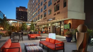 An outdoor seating area with orange sofas and striped ottomans, a large planter, and a modern sculpture. - Aloft Atlanta Downtown (Atlanta)