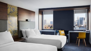 A hotel room with two beds, a desk, a chair, and a large window with a city view. - Aloft Atlanta Downtown (Atlanta)