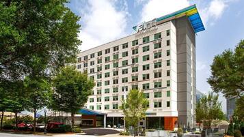 A modern hotel with a flat roof, multiple floors, and a prominent logo on the top.