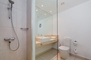Une salle de bain moderne avec une douche à parois de verre, un lavabo avec un porte-serviettes et des toilettes.