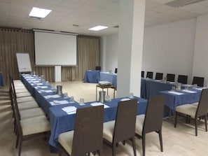 A conference room with a long table, chairs, a projector screen, and a whiteboard. - Napa Plaza Hotel-adults Only (AYIA NAPA)