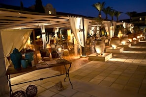 Ein Terrassenbereich im Freien mit Tischen, Stühlen und Dekorationselementen.