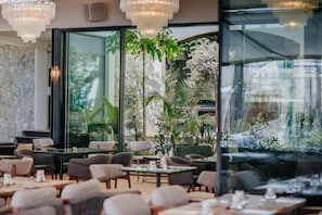 Ein Restaurant mit Innenbereich, großen Fenstern und Blick auf Grünflächen.