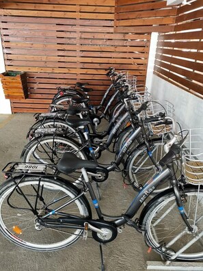 A row of bicycles parked against a wooden wall with a concrete floor. - Napa Plaza Hotel-adults Only (AYIA NAPA)
