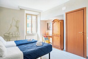 Un dormitorio con dos camas, un armario de madera, un escritorio y una ventana.
