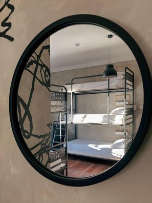 Habitación con literas y un espejo redondo en la pared.
