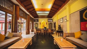 Eine geräumige Lobby mit Holzmöbeln, einer zentralen Sitzgruppe und einer großen Buddha-Statue.