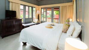 Ein Schlafzimmer mit einem großen Bett, einem Fernseher auf einer Holzkommode und einem Balkon mit Vorhängen.