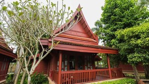 Ein traditionelles Gebäude mit rotem Dach, einer Veranda und einem Baum im Vordergrund.