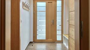A hallway with a wooden door with frosted glass panels, a coat rack, and a bench. - Schmitten Finest Apartment - LEO (Zell am See)