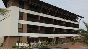 A multi-story hotel with balconies, outdoor seating, and a pool area. - CPG02 Flat Piscina Privada em Porto (Ipojuca)