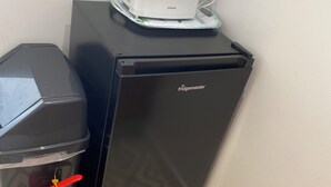 Une petite cuisine équipée avec un réfrigérateur noir, un grille-pain blanc et un extincteur rouge.