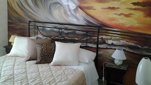 A bed with a quilted cover, a headboard with a wave painting, and a nightstand with a lamp. - B & B Paradise (Melendugno)