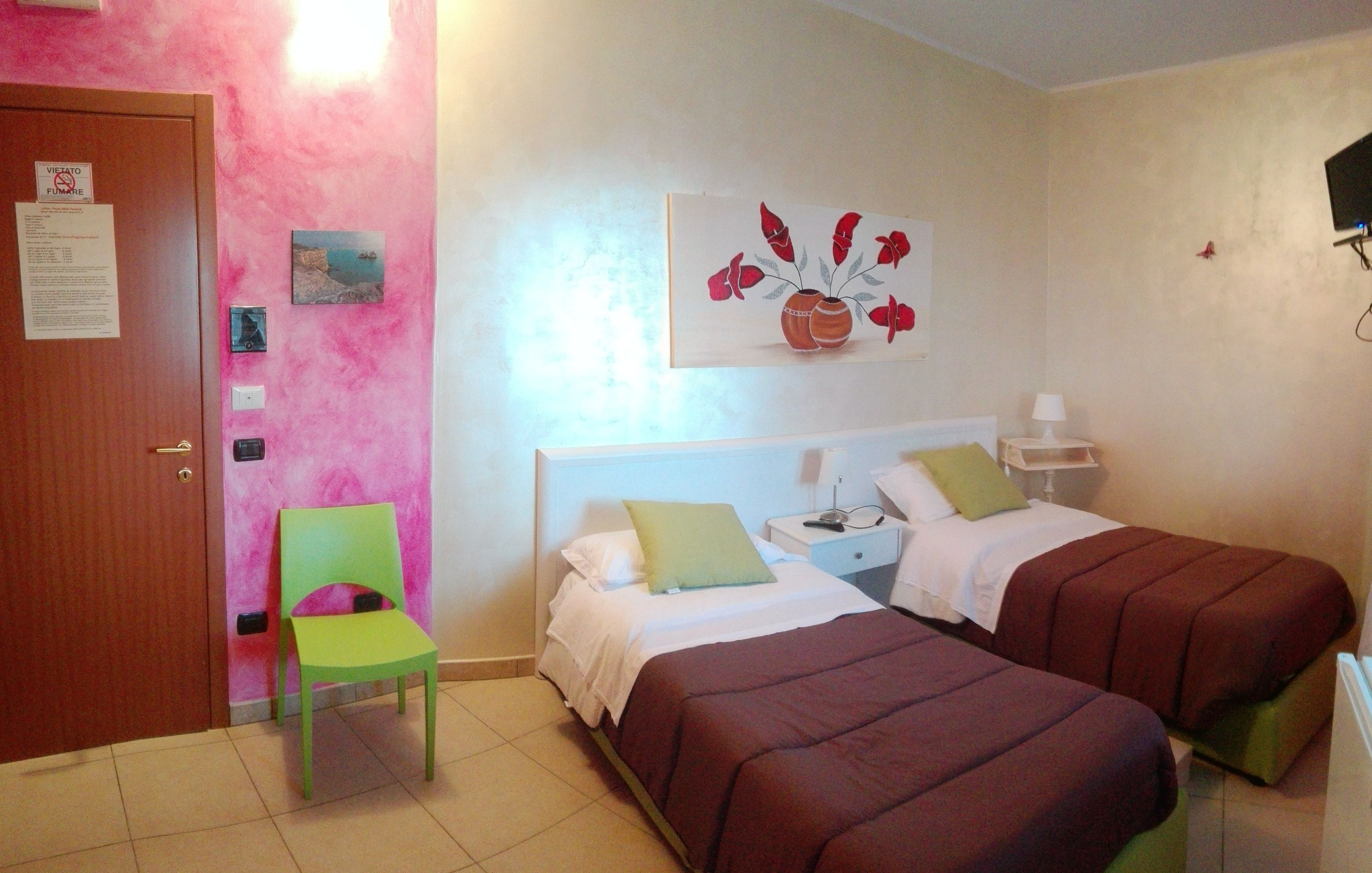 A room with two beds, a chair, a nightstand, a lamp, and a painting on the wall.