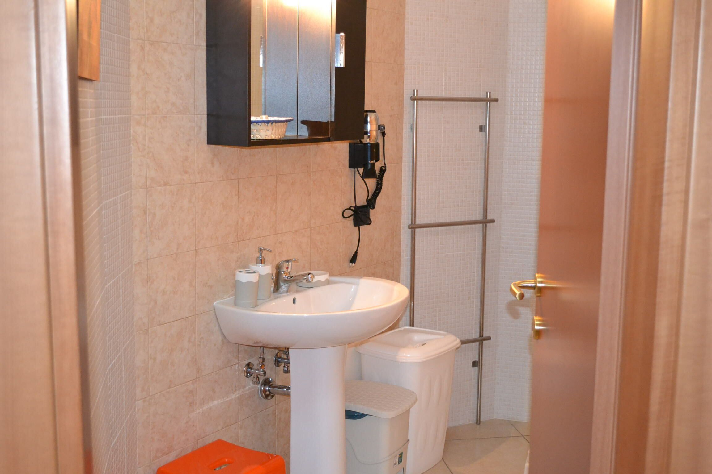 A bathroom with a white sink, a mirror, a towel rack, and a shower area.