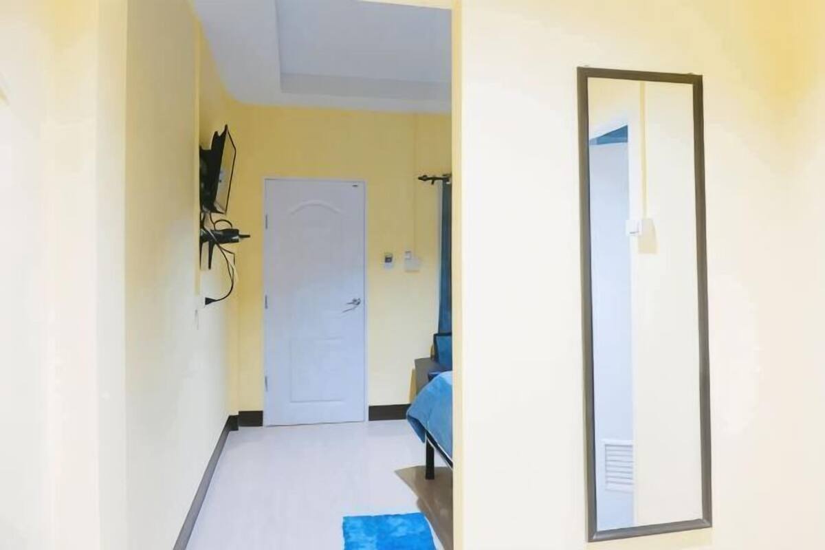 A hallway with a white door, a blue bench, and a mirror on the wall.