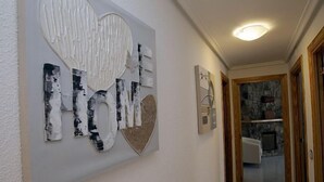 Un pasillo con una obra de arte moderno en la pared, una chimenea de piedra y vistas a una habitación con un sofá blanco.