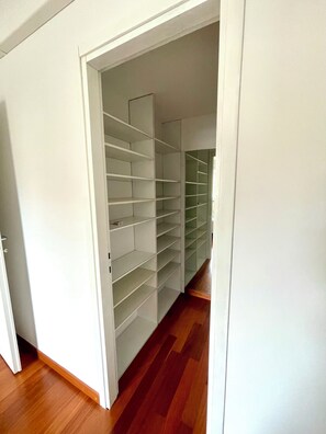 Corredor que leva a um armário com várias prateleiras.