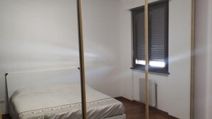 Un dormitorio con cama, ventana con persianas y radiador.