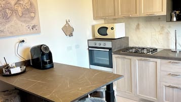 Cozinha moderna com bancada de mármore, máquina de café, micro-ondas e fogão a gás.