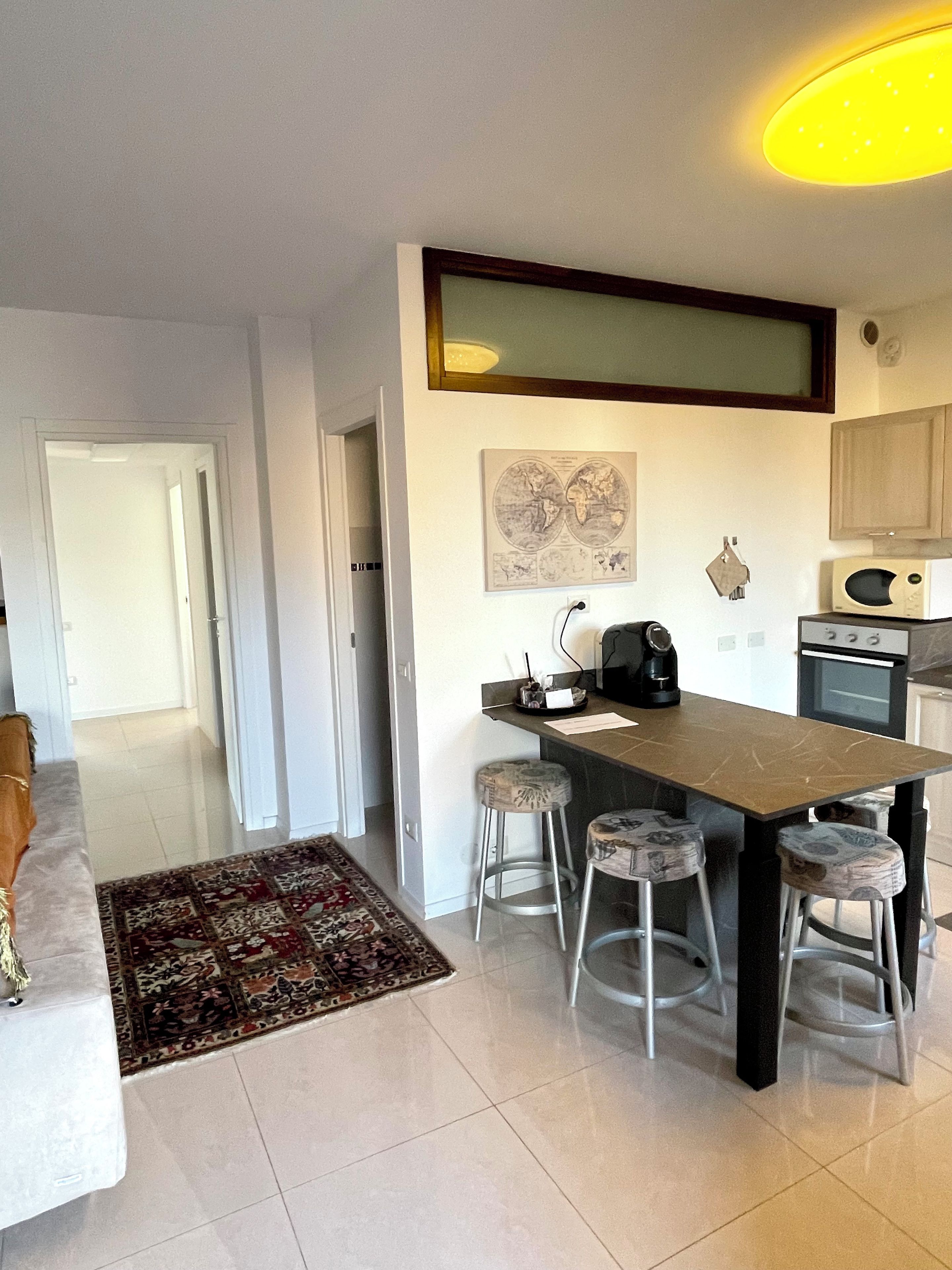 A modern kitchen with a central island, bar stools, a microwave, and a stove.