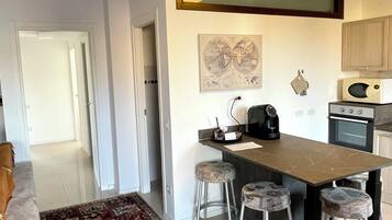 A modern kitchen with a central island, bar stools, a microwave, and a stove.