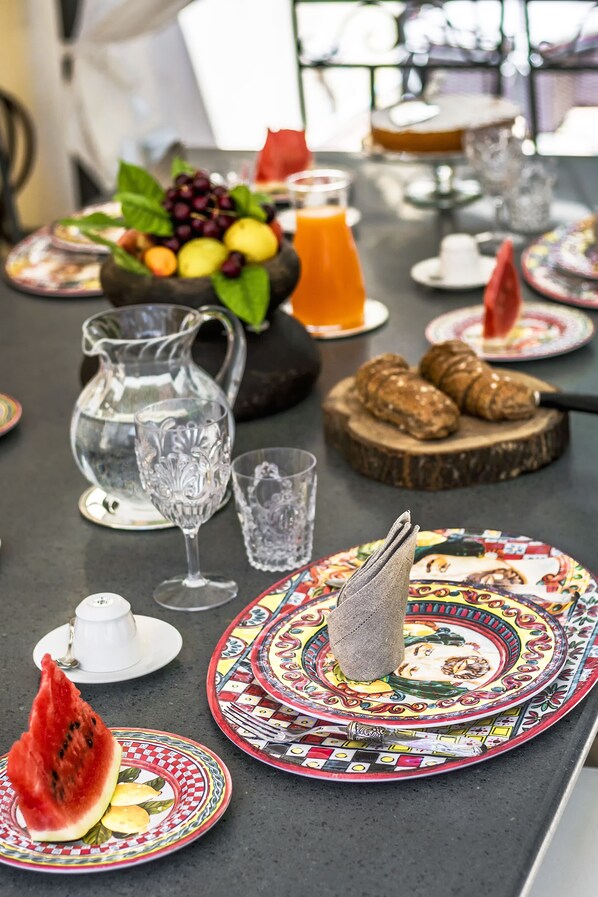 A dining table with various plates, a pitcher, glasses, and a fruit bowl. - Relais 147 (Taormina)