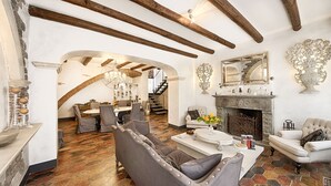 A spacious living area with a fireplace, a dining area, and a staircase leading to an upper level. - Relais 147 (Taormina)