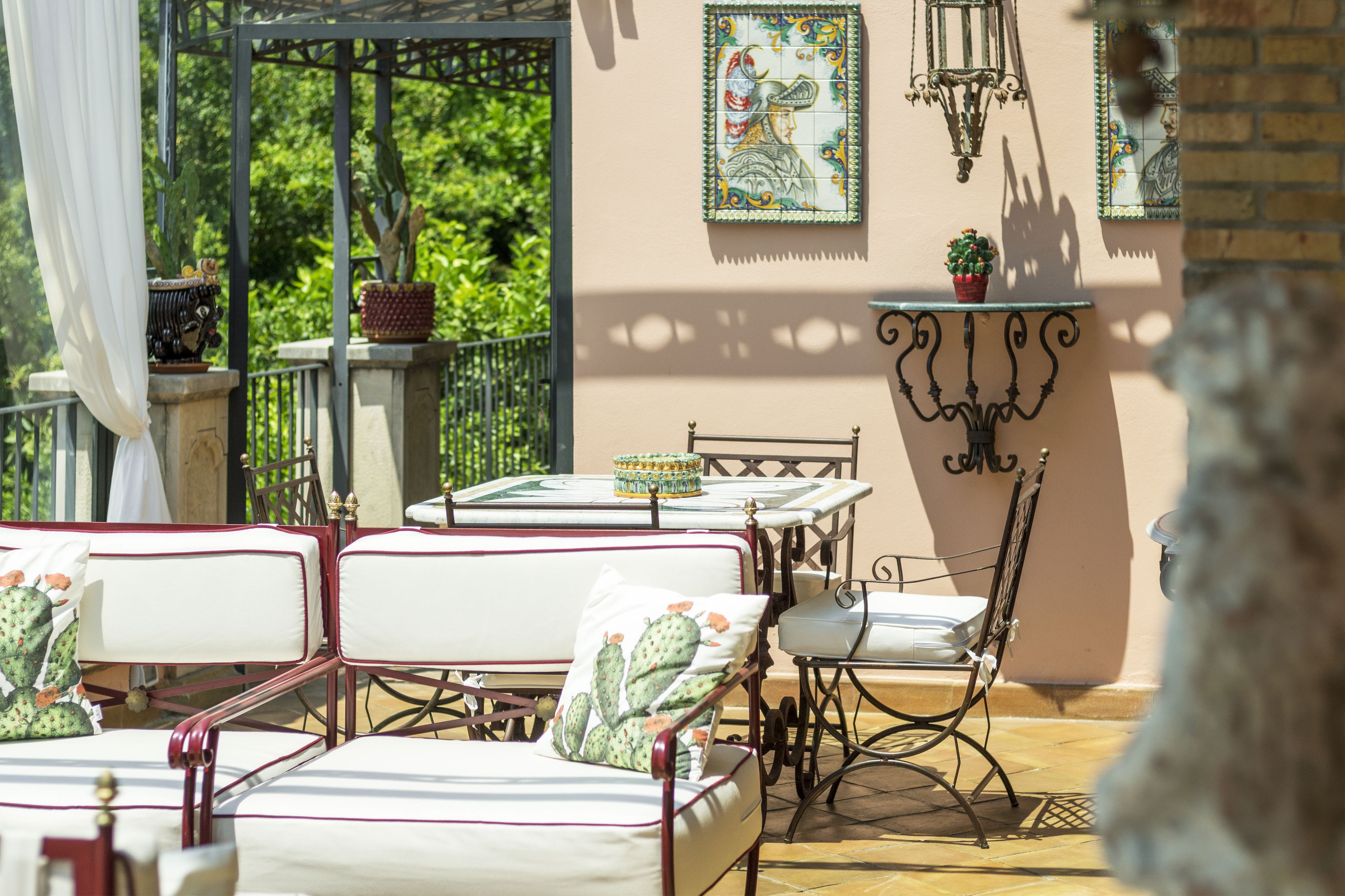 A sunlit patio with outdoor seating, a table, and decorative tiles.