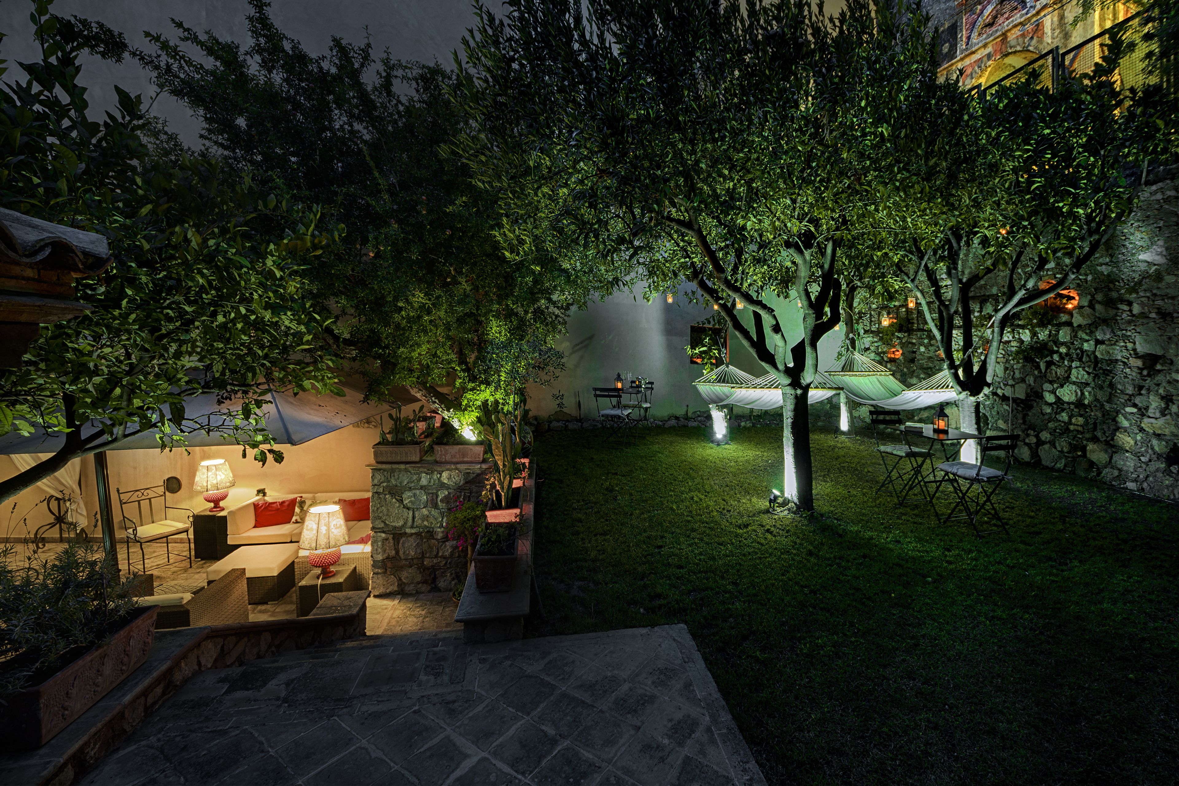 Un espace extérieur aménagé en terrasse, avec des marches en pierre, un coin salon doté de coussins et un hamac.