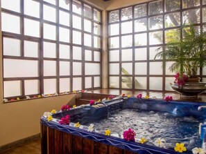 A spa area with a hot tub, large windows, and a potted plant. - Mercure Goa Devaaya Resort (Panaji)