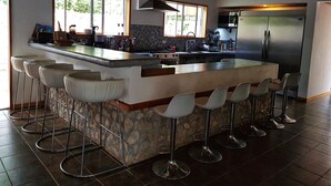 Una cocina moderna con una isla grande, taburetes de bar y una pared de acento de piedra.
