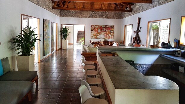 Una habitación amplia con techo alto, una barra alargada y una disposición de asientos.