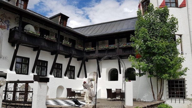 Un edificio tradizionale con un cortile interno, scalinate in pietra e una statua.