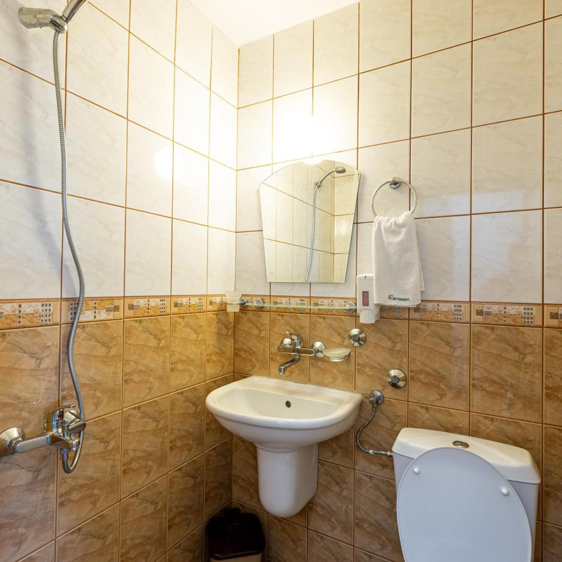A bathroom with a shower, sink, toilet, and a towel rack.